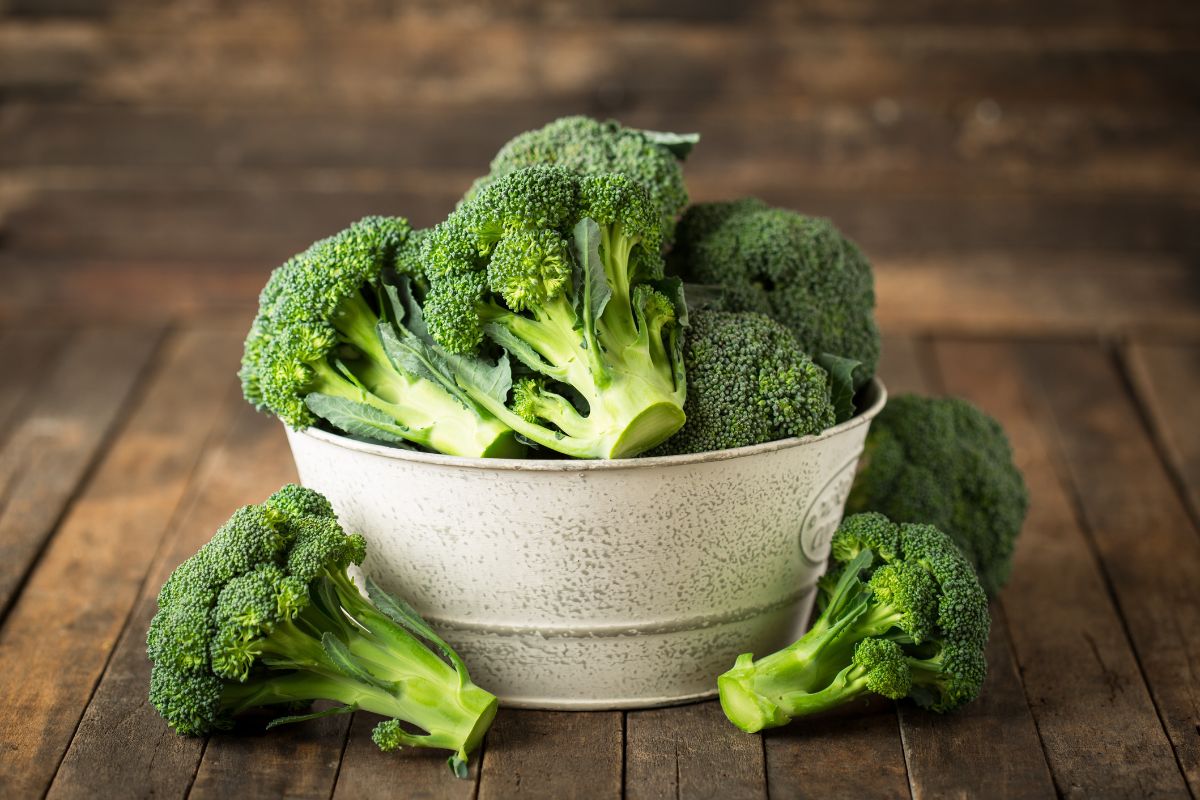 A bowl full of organic broccoli on a wooden table.