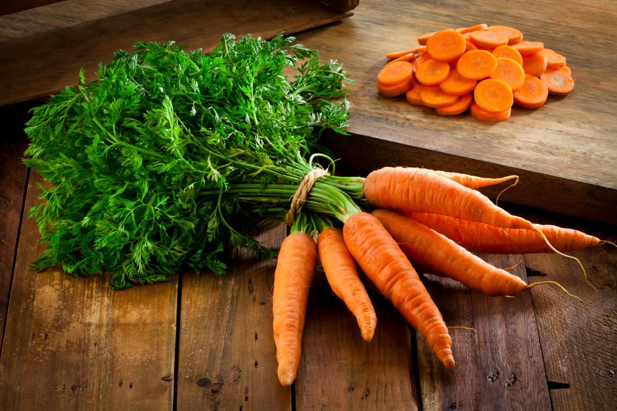 A pack of organic carrots with slices of carrots on a wooden table.